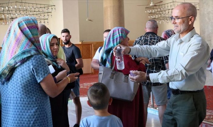İzmir’de camiyi ziyeret eden turistlere 15 dildeki Kur’an-ı Kerim kitapçıklarını hediye ediyor